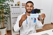 © Krakenimages.com - Young middle east man wearing doctor uniform holding medical mask at clinic
