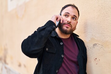 Wall Mural - Young hispanic man talking on the smartphone at street