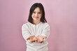 © Krakenimages.com - Woman with down syndrome standing over pink background smiling with hands palms together receiving or giving gesture. hold and protection