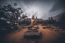 Golden Statue Of Buddha Sits On A Rock In The Mountains Of Arizona During A Winter Snow