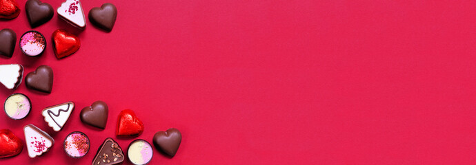 Wall Mural - Valentines Day chocolate corner border. Red and pink heart theme. Top view on a red paper banner background with copy space.