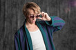 relaxed dude after a party in a housecoat with a shaggy head, posing in the studio on a gray background. Close-up with funny faces in sunglasses