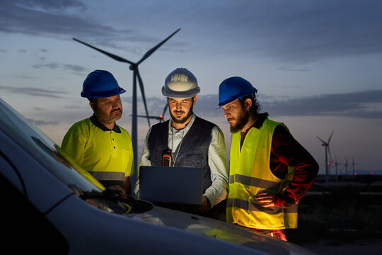 group of engineers in discussed the plan for the maintenance of wind turbines working with a laptop 