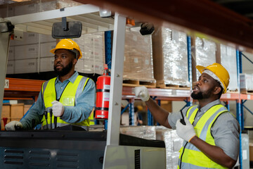 Two African workers working in a warehouse Organize the product system with a forklift truck. transportation industry.