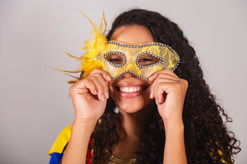 Beautiful black Brazilian woman, with frevo outfit, and umbrella, carnival. putting carnival mask on face.