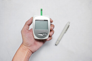 asian man hand holding a blood glucose check tool (glauco meter) isolated on white background top view.