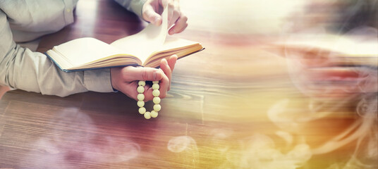 Wall Mural - Reading religious literature. A man studies the Koran and sorts out the rosary.