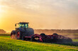 Leinwandbild Motiv tractor in the field under sunset light, tillage in spring, preparation for sowing. High quality photo