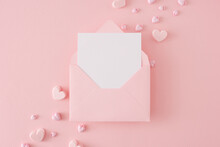 Valentines Day Concept. Flat Lay Composition Of Pink Heart Shaped Baubles On Pastel Pink Background And Envelope With Letter In The Middle. Lovers Holiday Card Idea.