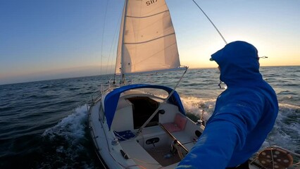 Wall Mural - Young sailor recording selfie from Sailboat in open sea during sunset. travel, adventure concept