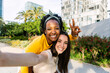 © Xavier Lorenzo - Two multiethnic female friends in casual summer clothes taking selfie self portrait using smartphone camera outdoors.