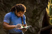 African American Rock Climber Looks Thought The Guide Book In Search Of The Next Climbing Problem.