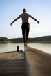 © Cavan Images - A man balances barefoot on a rail of a wooden pier at the shores at one of the thousands of lakes in the Saimaa region of Finlan