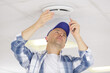 electrician installing smoke detector on ceiling