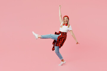 Wall Mural - Full body excited happy cool fun young woman wear white t-shirt red hat stand on toes raise up leg leaning back with outstretched hands isolated on plain pastel light pink background studio portrait.