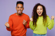 © ViDi Studio - Young couple two friends family man woman of African American ethnicity wear casual clothes together do winner gesture celebrate clench fists say yes isolated on pastel plain light purple background.