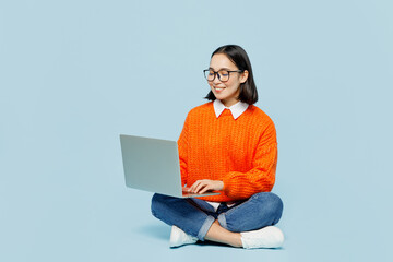 full body young it woman of asian ethnicity wear orange sweater glasses hold use work on laptop pc c