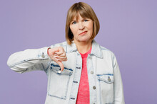 Elderly Dissatisfied Displeased Blonde Woman 50s Years Old Wear Casual Clothes Denim Jacket T-shirt Showing Thumb Down Dislike Gesture Isolated On Plain Pastel Light Purple Background Studio Portrait.