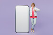 © ViDi Studio - Full body elderly blonde woman 50s years old wear casual clothes denim jacket t-shirt big huge blank screen mobile cell phone with area show thumb up isolated on plain pastel light purple background.