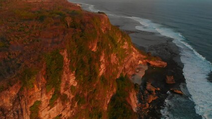 Wall Mural - Aerial view of cliffy coastline with ocean at sunset tones in Uluwatu, Bali