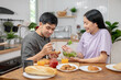 © Pormezz - happy family together. Asian couple eating breakfast in the kitchen.
