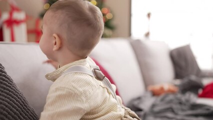 Sticker - Adorable toddler standing by christmas tree with serious expression at home