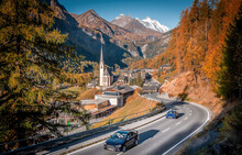 Incredible Scenery Of European Alps In Sunny Morning. Heiligenblut Church In Austria With Grossglockner Peak In Background Grossglockner High Alpine Road Is A Most Popular Place Of Travel