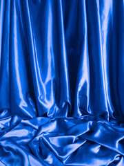 Royal blue textile background. Elegant smooth blue satin fabric. Silk fabric drapes. Luxurious cloth textile with liquid wave. Fabric shiny glitter  texture. Luxurious ultramarine sparkle background.