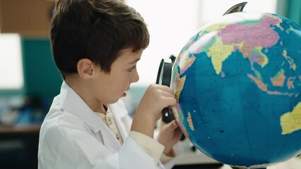 Poster - Adorable hispanic boy student looking earth using magnifying glass at laboratory classroom