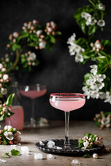 Spring and summer refreshing pink cocktail with apple blossom on light background. Pink summer cocktail