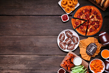 Wall Mural - Super Bowl or football theme food side border. Pizza, hamburgers, wings, snacks and sides. Top down view on a dark wood background.