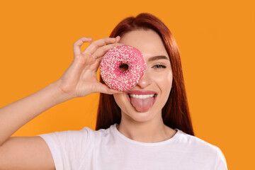 Poster - Happy woman with red dyed hair and donut on orange background