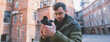 © Anna - Portrait of a young male photographer with a camera takes a photo or video on the street, in an old courtyard.
