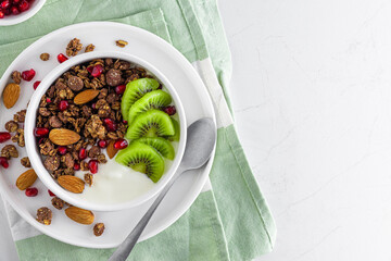 Wall Mural - Healthy breakfast. Bowl of chocolate oat homemade granola with fresh fruits and berries over napkin with a spoon