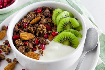 Wall Mural - Greek yogurt with chocolate granola, kiwi fruit, pomegranate seeds and almonds in a bowl