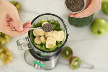 Man Adding Chia Seeds Into Blender With Ingredients For Smoothie At Table, Above View