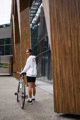 Wall Mural - Young african american woman looking at camera while walking near building on street 