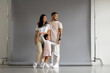 © Dmytro Hai - Positive young asian family holding hand of toddler daughter on grey