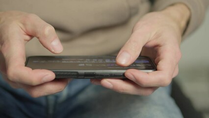 Aufkleber - A man's finger touches a monitor to scroll a page on a mobile phone. Viewing photos and documents in the smartphone library. A man in his hands uses a smartphone, turns pages.
