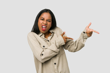 Wall Mural - Young Indian woman cut out isolated on white background pointing with forefingers to a copy space, expressing excitement and desire.