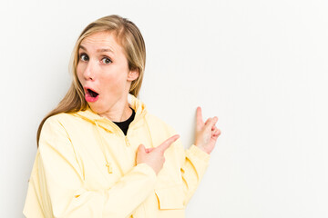 Young caucasian woman isolated on white background pointing with forefingers to a copy space, expressing excitement and desire.