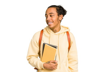 Young african american student man holding a book looks aside smiling, cheerful and pleasant.