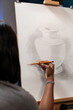 © DC Studio - Unrecognizable female artist making pencil drawing on canvas in home art studio. African american talented sketcher student creating masterpiece homework at home sketch atelier.