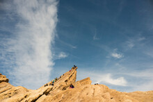 People Climb At Jagged Rock Formation In The California Desert.
