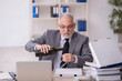© Elnur - Old male employee drinking alcohol at workplace