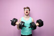 © Богдан Маліцький - non-athletic guy in glasses holds heavy dumbbells on a pink background and trains, motivated nerd goes in for sports