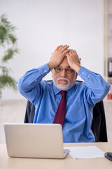 Wall Mural - Old male employee working in the office