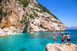 People jumping from the cliff into turquoise waters of Cala Mariolu, Sardinia, Italy