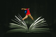 © Creativa Images - Male student jumping over a big open book