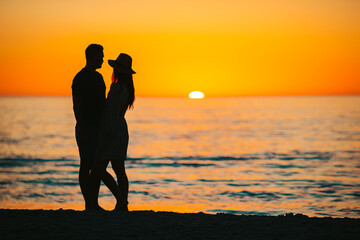 Happy couple on the beach at beautiful sunset on background